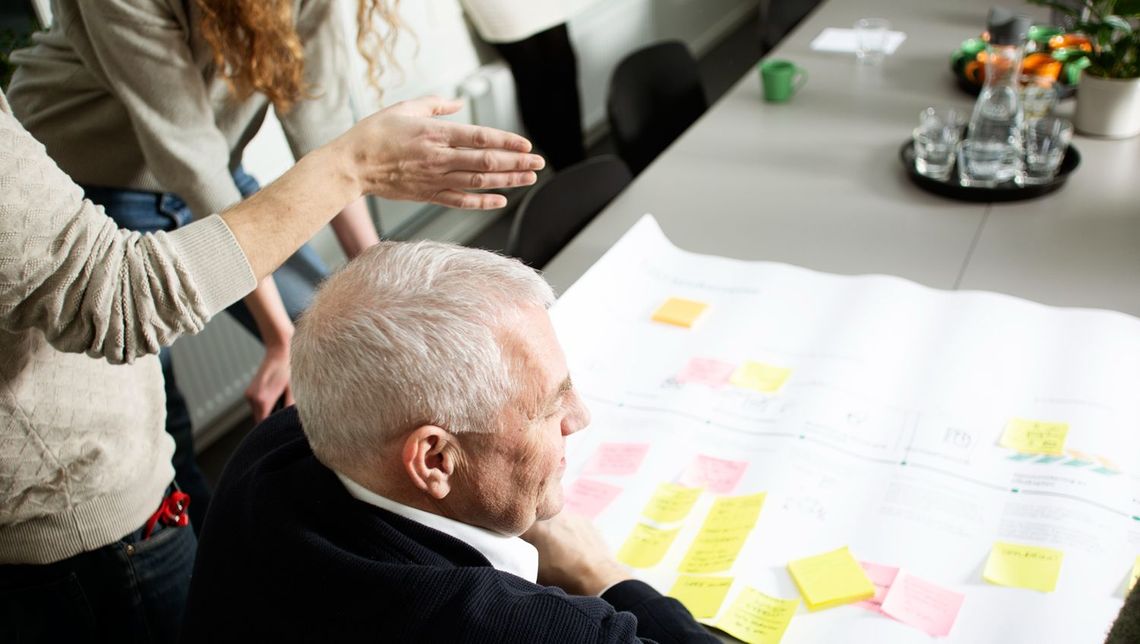 folk som sitter med post it lapper rundt et bord og diskuterer